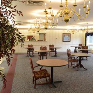 A spacious dining area featuring elegant chandeliers and neatly arranged tables and chairs.