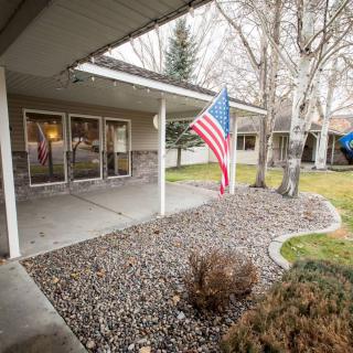 A suburban house with a patio featuring an American flag and garden.