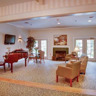 A cozy living room with a piano, fireplace, and comfortable seating.