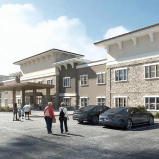 A modern building with a stone facade, featuring people walking in the parking lot during daytime.