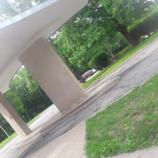 A view of an architectural structure with surrounding greenery and a roadway.