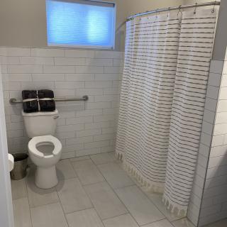 A clean and spacious bathroom featuring a toilet, shower with a curtain, and tiled flooring.