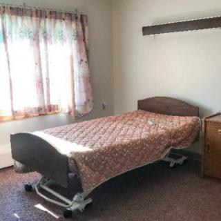 A simple room with a hospital bed and a window with curtains.