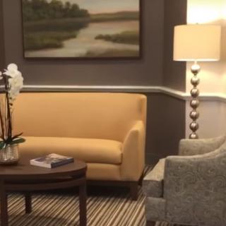 A cozy living room setup with a yellow sofa, grey armchair, and a warm lamp.