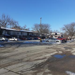 A sunny winter day in an apartment parking lot, with vehicles parked amidst a backdrop of clear blue skies.