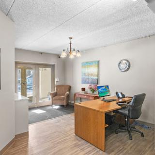A modern office space featuring a wooden desk, comfortable seating, and ample natural light.