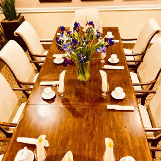 A neatly set dining table with a bouquet of flowers in the center.
