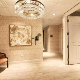 A luxurious hallway with a chandelier and artwork on the wall.