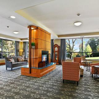 A spacious and well-lit lobby area with comfortable seating, a central fireplace, and large windows offering scenic views.