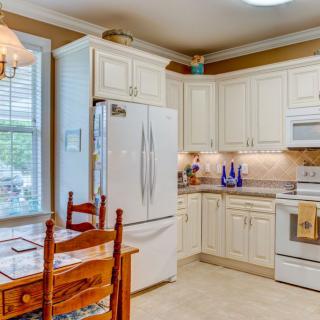 A cozy kitchen with white cabinetry, a dining area, and modern appliances.