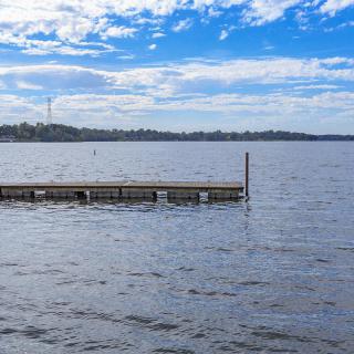 A serene lake with a floating dock under a partly cloudy sky.