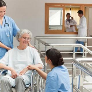 Healthcare professionals assisting an elderly patient in a hospital setting.