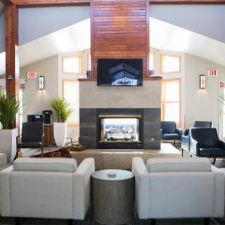 A stylish and inviting lounge area featuring a modern fireplace, comfortable seating, and abundant natural light.