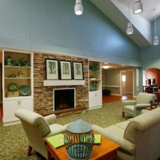 A cozy and modern living room with a fireplace, sofas, armchairs, and decorative shelves.