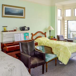 A cozy bedroom with twin beds, a couple of chairs, and large windows letting in natural light.