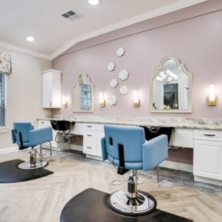 A stylish beauty salon interior with blue chairs, decorative mirrors, and soft lighting.
