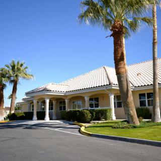 A sunny day view of a building entrance with palm trees and a clear blue sky.