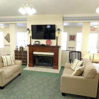 A cozy living room with sofas, a fireplace, and a television mounted above.