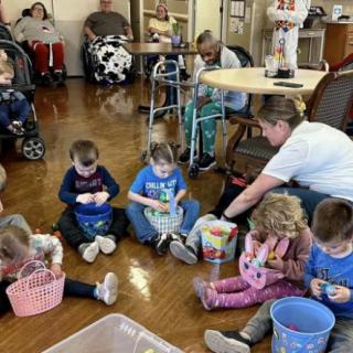 Children and elderly people engage in a group activity indoors.
