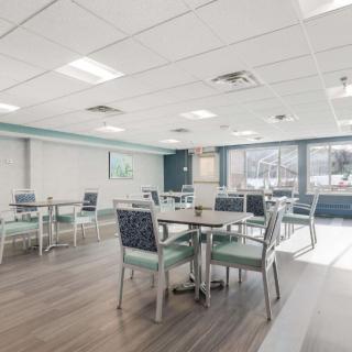 A modern dining area with multiple tables and chairs, well-lit by natural and artificial light.