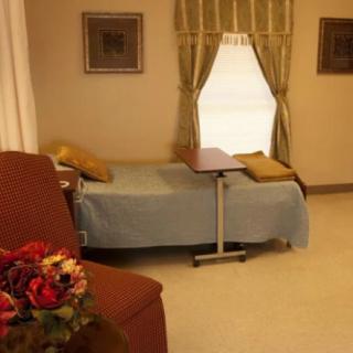 A cozy hospital room with a single bed, side table, curtains, and wall decorations.