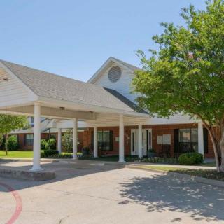 A view of a large building with a covered entrance and surrounding trees.