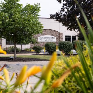 A view of a landscaped area featuring flowers and trees in front of a building.