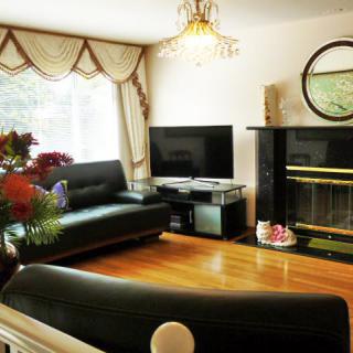 A cozy living room with a dark sofa, television, and fireplace, featuring elegant decor and hardwood flooring.