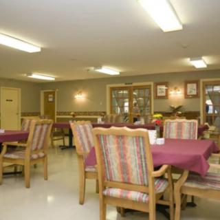 A community dining area with tables and chairs arranged under bright lighting.