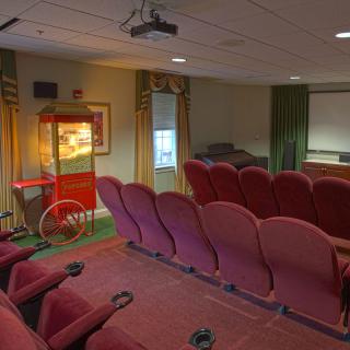 A cozy home theater setup with red seats, a projector, and a popcorn machine.
