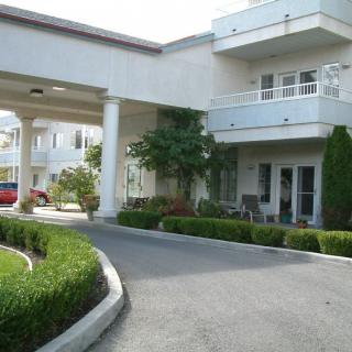 A modern building entrance with a circular driveway and landscaped greenery.