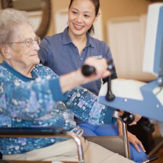 A caregiver assists an elderly woman with her physical therapy exercises, promoting health and well-being.
