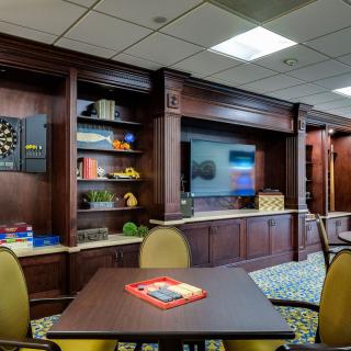 A modern lounge with a dartboard, television, and seating area.