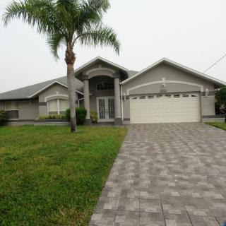 A suburban house with a palm tree and a paved driveway.
