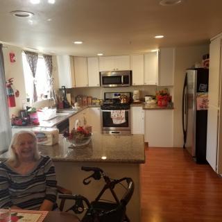 A modern kitchen with an elderly person sitting in a wheelchair.