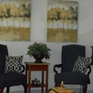A cozy seating area with two chairs, decorative pillows, a small table, a plant, and wall art.