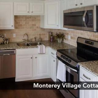 A modern kitchen with white cabinets and stainless steel appliances at Monterey Village Cottage.