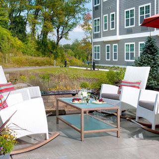 A cozy outdoor patio setup with comfortable chairs and a table in front of a modern building.