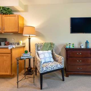 A cozy living room corner with an armchair, side table, and wall-mounted television.