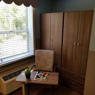 A cozy corner of a room featuring a desk, chair, and storage cabinet by the window.