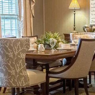 A cozy dining room setup with a wooden table, elegant chairs, and decorative elements.