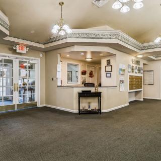 A spacious and well-lit lobby with a reception desk, carpeted floor, and decorative elements.