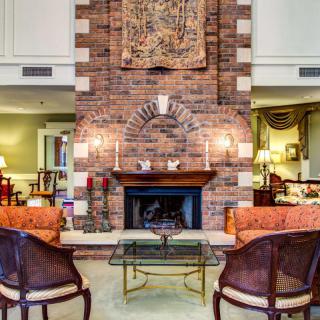 A cozy living room featuring a brick fireplace, elegant seating, and warm decor.