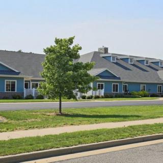 A row of suburban residential homes with a grassy lawn and tree in front.