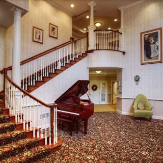 A grand staircase with a wooden banister, accompanied by a classic piano and elegant decor.