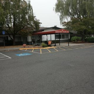 A view of a commercial building with a parking lot and trees in the vicinity.