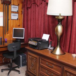 A cozy home office setup with a computer, desk, printer, and lamp.