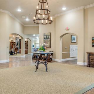 A spacious and elegantly decorated lobby with a central table and a large chandelier.