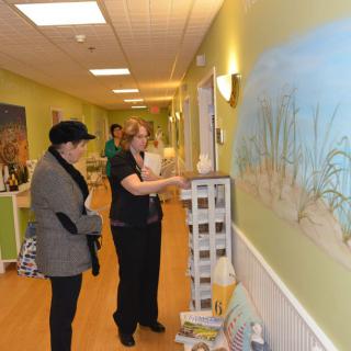 Two people engage in a discussion while observing artwork in a hallway.