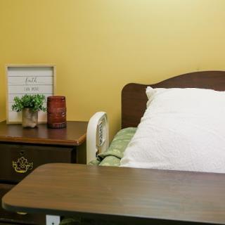 A simple hospital room with a bed and nightstand.